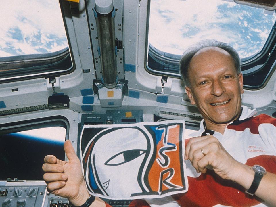 Claude Nicollier arbore le logo de la TSR depuis la navette spatiale Columbia, 1996.