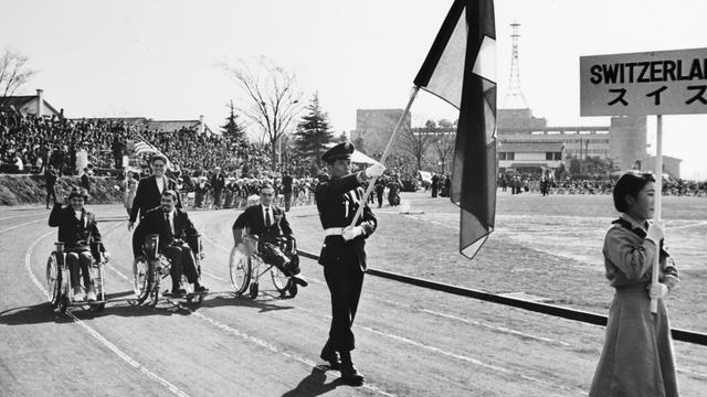 La délégation suisse lors de la cérémonie d'ouverture des Jeux paralympiques de Tokyo en 1964. [KEYSTONE/Str]