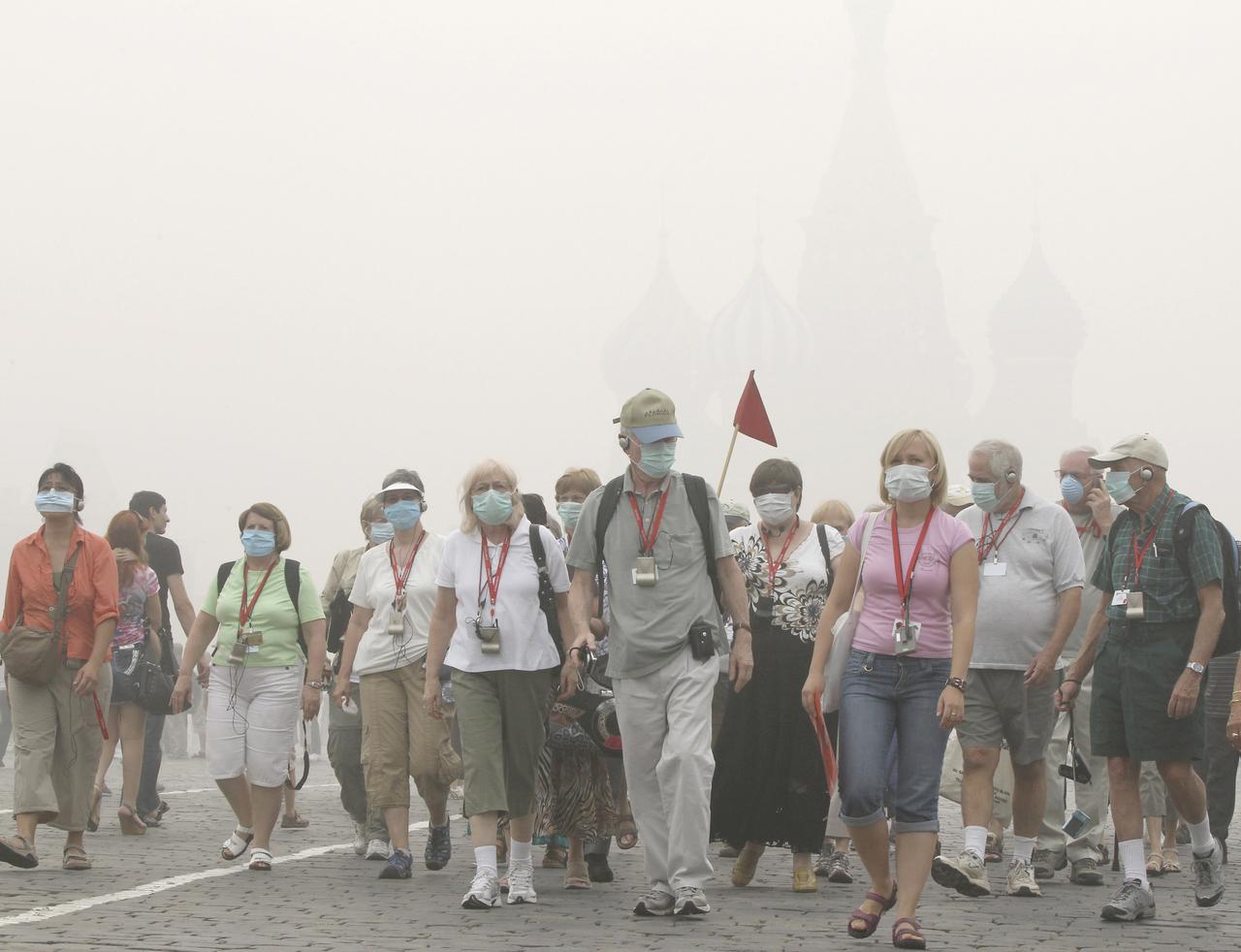 Tourists, wearing masks to protect themselves from the smell of heavy smog caused by peat fires in nearby forests, walk along Red Square in central Moscow August 7, 2010. Dense clouds of acrid smoke from peat and forest fires choked Russia's capital on Friday, seeping into homes and offices, diverting planes and prompting exhausted Muscovites to wear surgical masks to filter the foul air. [REUTERS - � Alexander Demianchuk / Reuters]