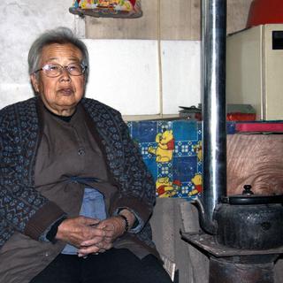 Mme Wang et son poêle: elle pourrait se chauffer à l'électrique, mais elle préfère le charbon... [Alain Arnaud]
