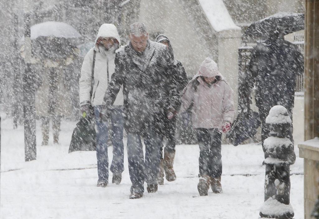 Les Londoniens ont dû s'accommoder des flocons de neige lors de leurs courses samedi. [KEYSTONE - Alastair Grant]