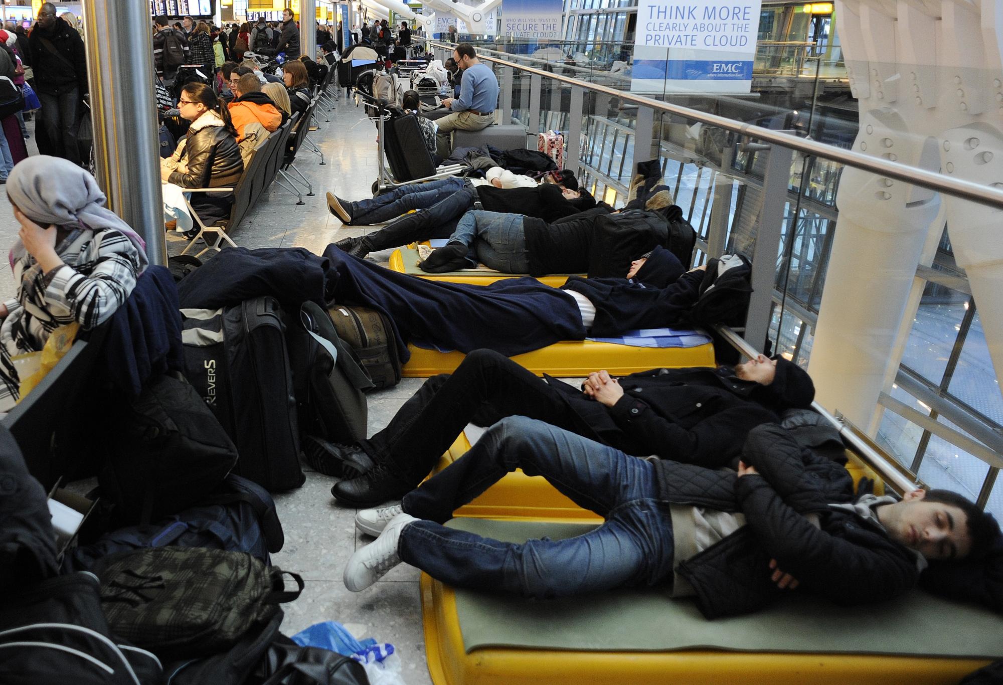 Des passagers tentent de dormir sur des lits improvisés dans le terminal 5 de l'aéroport d'Heathrow, à Londres. [Toby Melville]