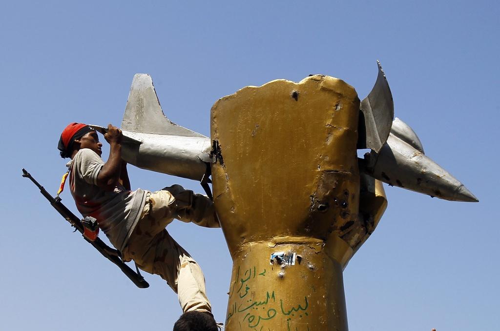 Un rebelle escalade la statue symbolisant le pouvoir de Mouammar Kadhafi, dans le quartier de Bab al-Aziziya. [KEYSTONE - Francois Mori]