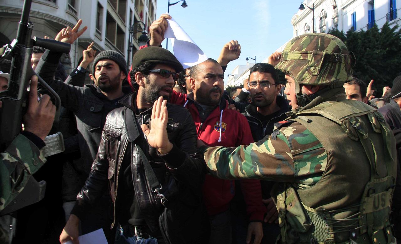 Protesters react to soldiers during a demonstration in downtown Tunis January 17, 2011. Tunisian security forces used water cannon, tear gas and fired shots in the air on Monday as demonstrators took to the streets demanding that the ruling party of the ousted president give up power. REUTERS/Zoubeir Souissi [REUTERS - oubeir Souissi]