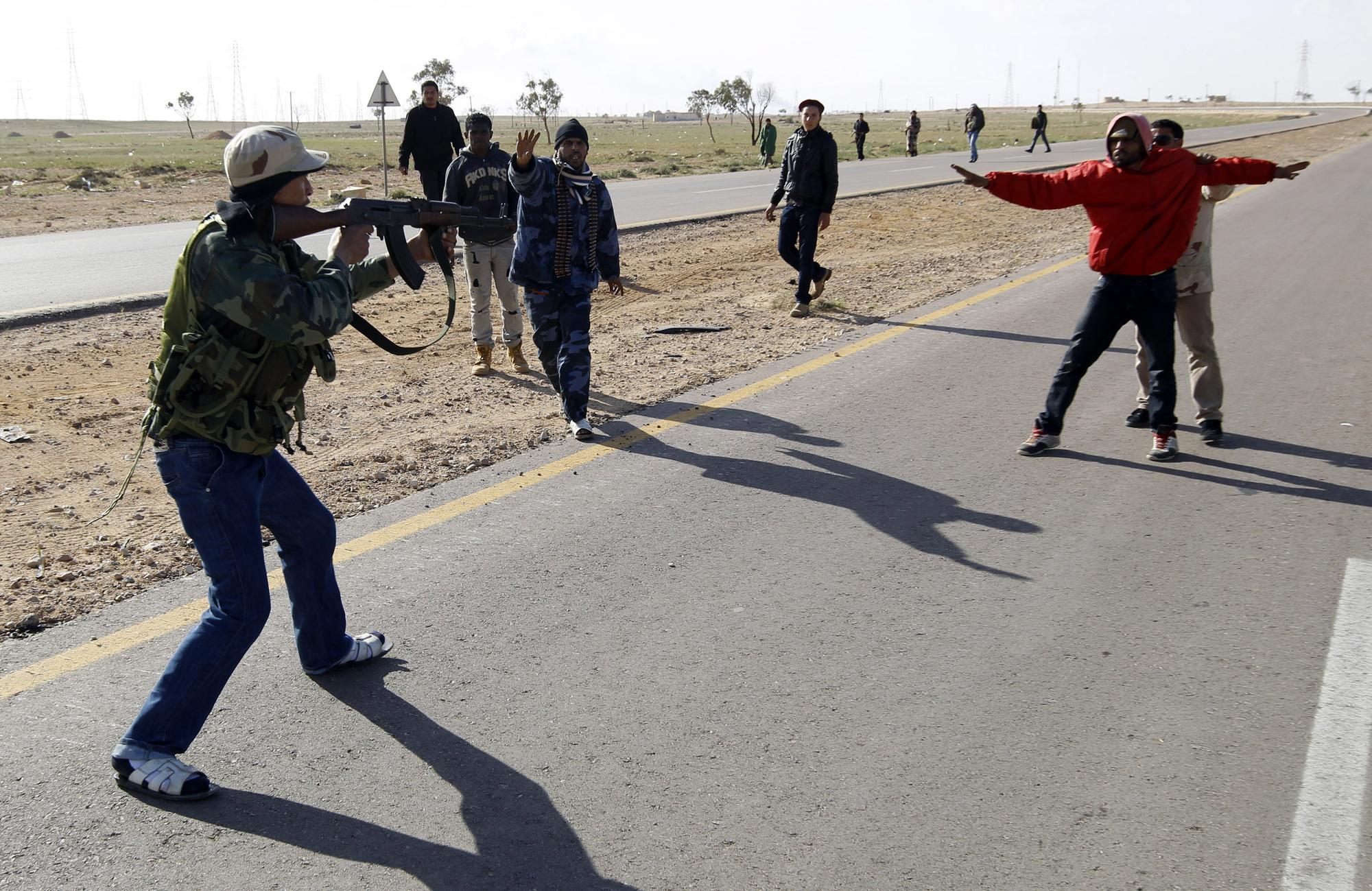 21 mars: des rebelles pointent leurs armes contre des personnes suspectées d'être fidèles à Kadhafi, sur la route entre Benghazi et Ajdabiya. [REUTERS - Goran Tomasevic]