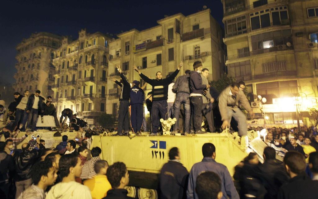 Un char de l'armée entouré de manifestants la nuit dernière au centre du Caire. [KEYSTONE - Ben Curtis]