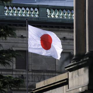 Un drapeau japonais flotte sur le toit de la Banque centrale du Japon. [EPA/Keystone - Franck Robichon]