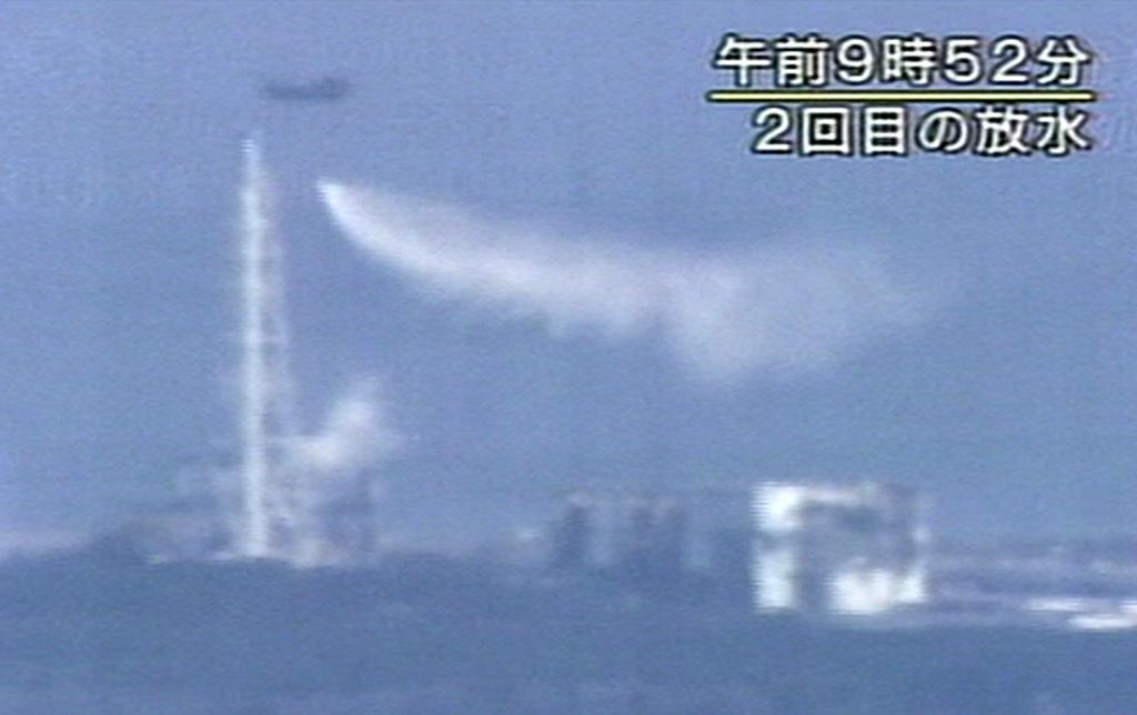 Un hélicoptère japonais déverse des masses d'eau sur le réacteur N°3 de la centrale. [KEYSTONE - NHK TV]