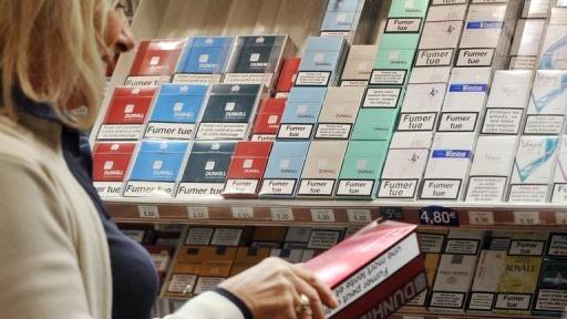 Une buraliste range des paquets de cigarettes dans son bureau de tabac