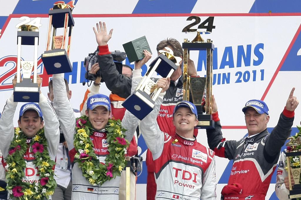 The Audi R18 TDI No2 drivers from left, Benoit Treluyer of France, Andre Lotterer of Germany and Marcel Fassler of Switzerland, andAudi Motorsport Chief Dr Wolfgang Ullrich react with their trophy on the podium, after the 79th 24-hour Le Mans endurance race, in Le Mans, western France, Sunday, June 12, 2011. (AP Photo/Vincent Michel) [KEYSTONE - Vincent Michel]