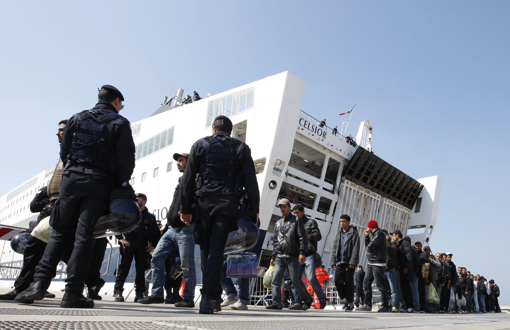 Des policiers et des immigrants sortent du ferry Excelsior au port de Tarente. [AFP - Carlo Hermann]
