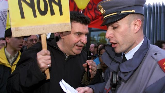 Josef Zisyadis, POP vaudois, est interpele par un policier de la ville de Lausanne au sujet du deplacement de la manifestation contre la fermeture de bureaux de poste, ce mercredi 13 fevrier 2002, a Lausanne. Quelque 400 personnes ont proteste contre la fermeture prevue d'un tiers des bureaux de poste de la capitale vaudoise. Les manifestants ont exige que La Poste renonce a ce projet, comme elle l'a fait pour le bureau de St-Jean a Geneve. (KEYSTONE/Fabrice Coffrini) [Fabrice Coffrini]