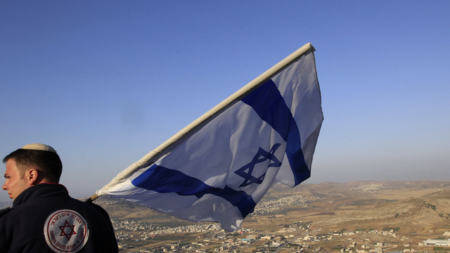 Un citoyen juif israélien lève le drapeau de l'Etat hébreu sur le Mont Gerizim qui surplombe la ville palestinienne de Naplouse [Reuters]