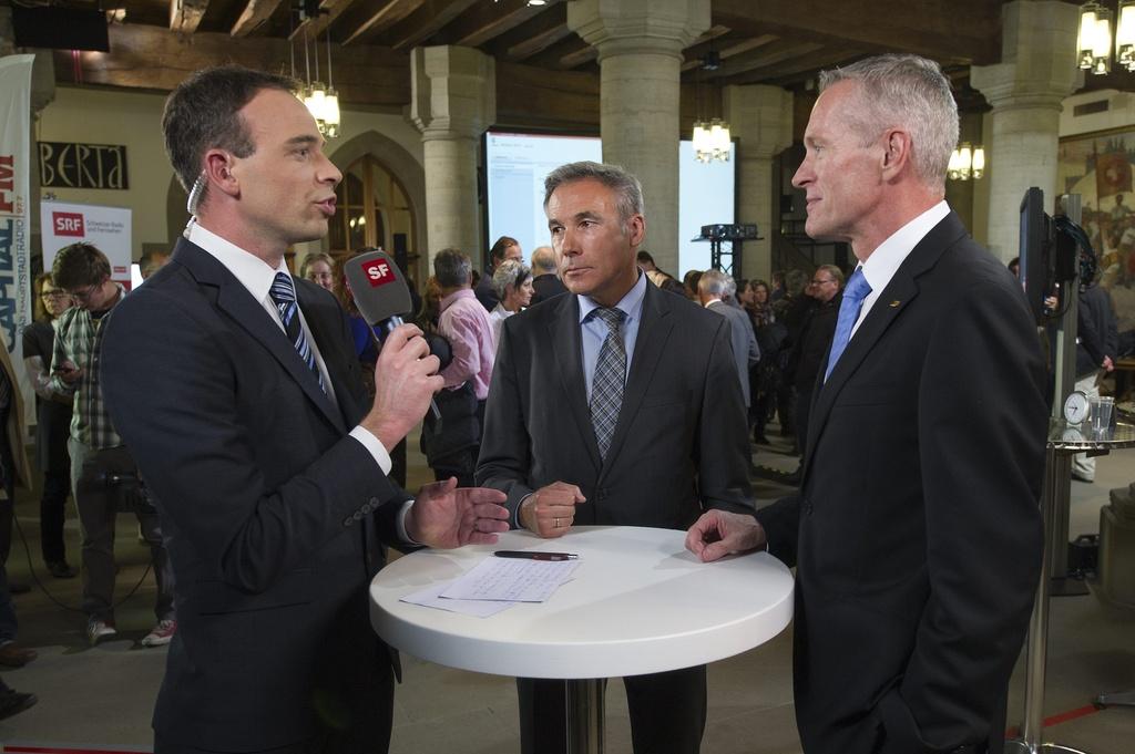 L'UDC Adrian Amstutz (milieu) et le PBD Werner Luginbühl (droite) au micro d'un journaliste de la télévision alémanique SF. [KEYSTONE - Peter Schneider]