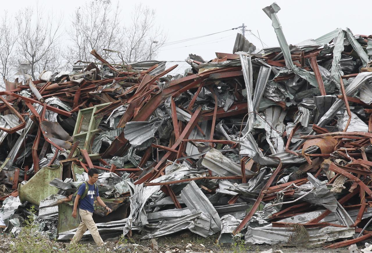 Un homme passe devant un pile de débris générés par le tsunami à Ishinomaki (préfecture de Miyagi). [Kim Kyung-Hoon]