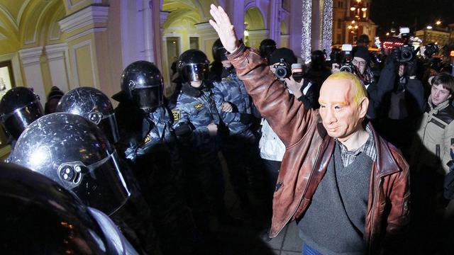 Un manifestant opposé à Vladimir Poutine porte un masque devant les forces de sécurité à Saint-Petersbourg le 8 décembre 2011. [Dmitry Lovetsky]