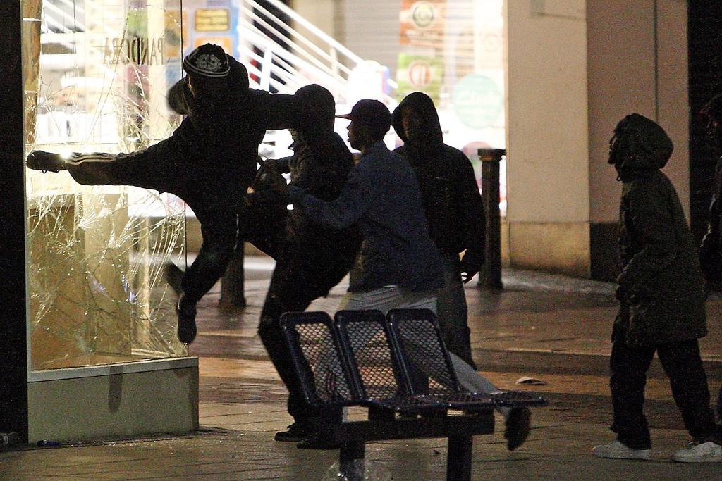 Ces jeunes brisent la vitrine d'un magasin dans un centre commercial. Après deux nuits d'émeutes à Londres, les violences se sont propagées à d'autres villes, comme ici à Birmingham (centre). [KEYSTONE - David Jones]
