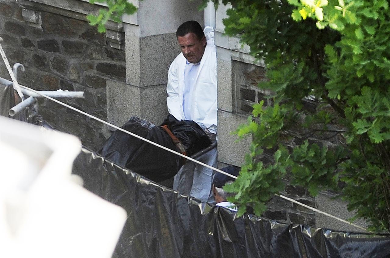 Un policier porte l'un des 5 corps découverts dans le jardin ce jeudi 21 avril. [Jean-Sébastien Evrard]