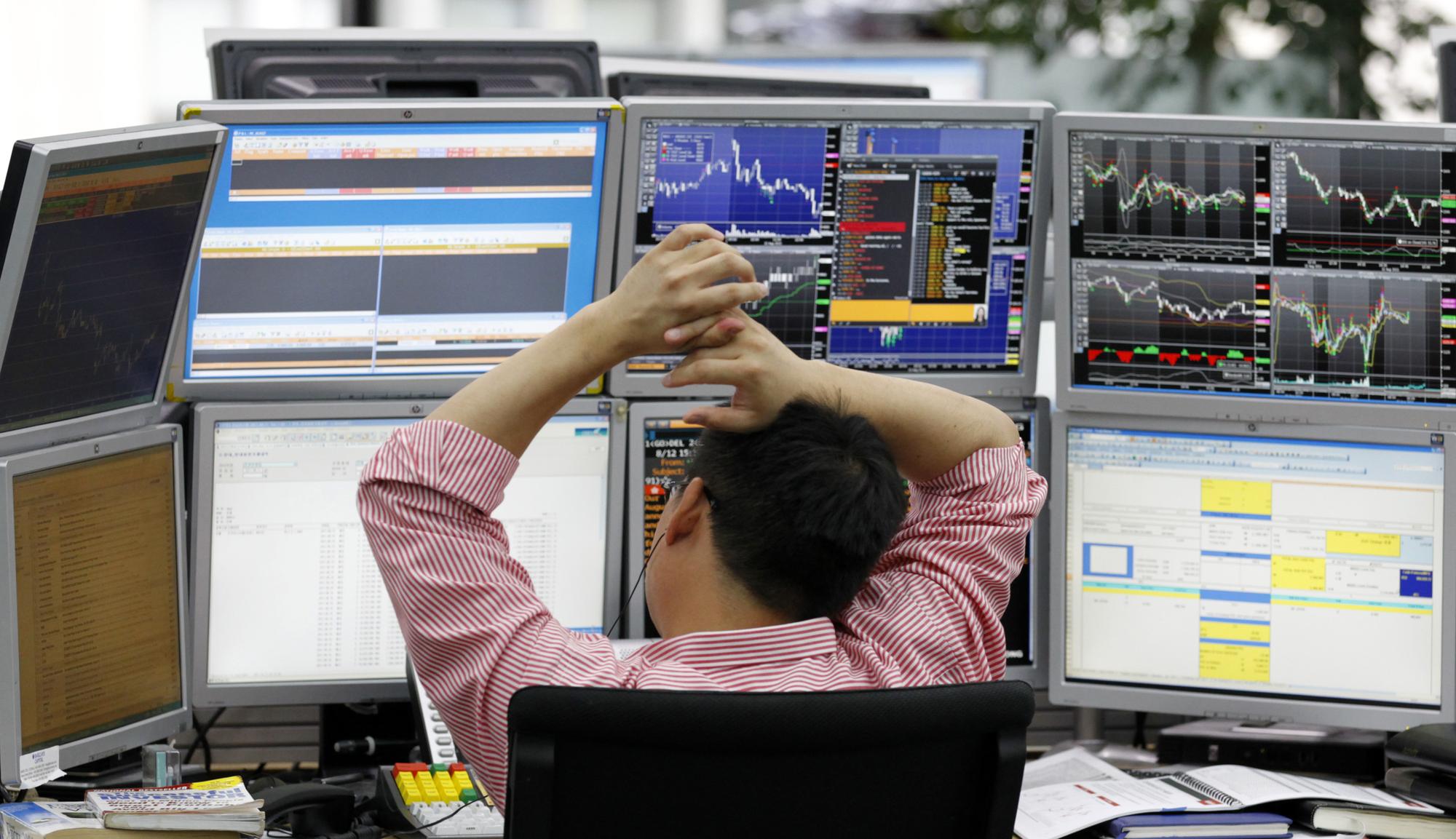Un revendeur de devises étrangères, samedi à la bourse de Séoul en Corée du Sud, n'est pas tout à fait rassuré par la volatilité des indices. [REUTERS - Lee Jae-Won]