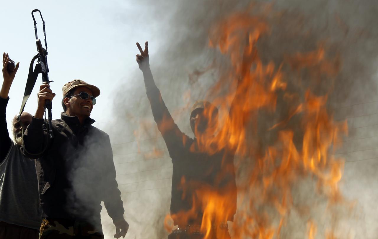 Des rebelles mettent le feu à des habits de soldats loyalistes sur la route entre Benghazi et Ajdabiya. [REUTERS - Goran Tomasevic]