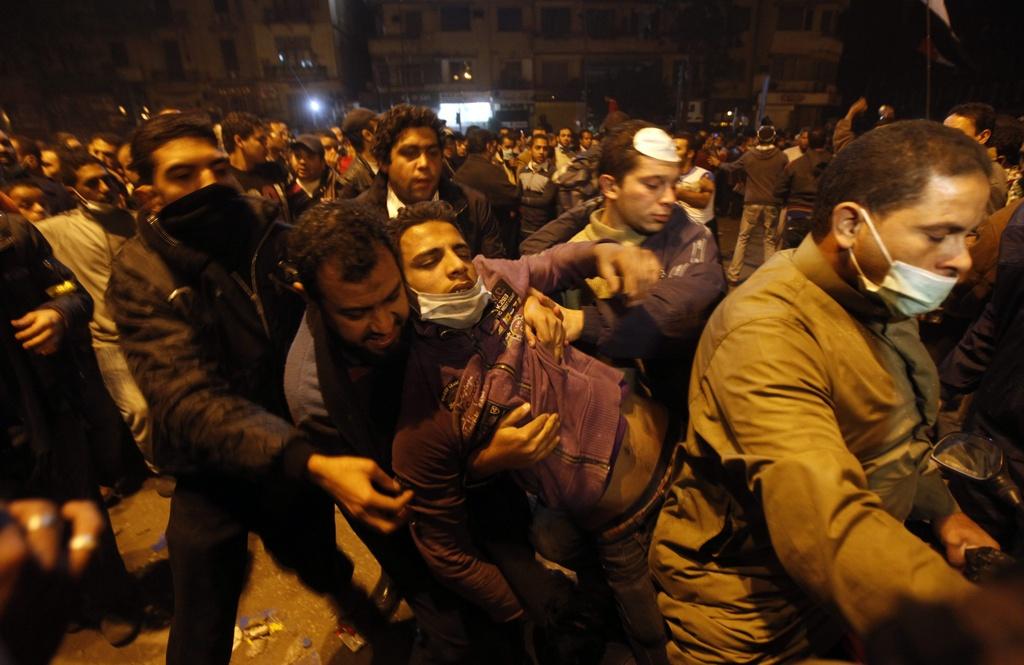 Sur la place Tahrir, des manifestants portent l'un d'entre eux, blessé. [Khalil Hamra]