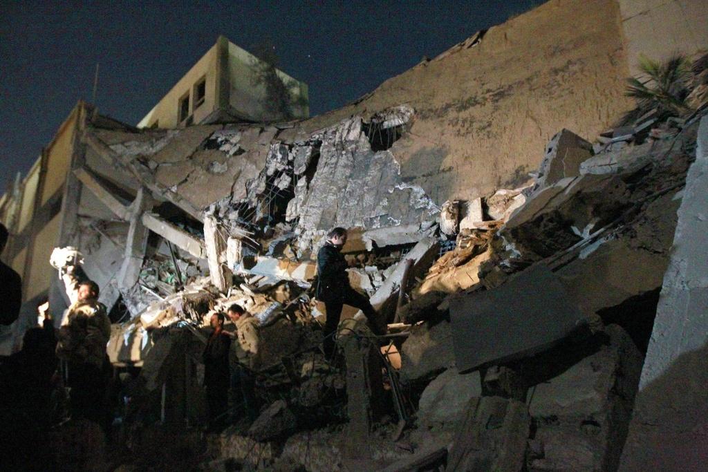 Des soldats libyens constatent les dommages causés par un tir de missile de la coalition sur un bâtiment administratif de la résidence Bab Al Aziza de Mouammar Kadhafi. [KEYSTONE - Jerome Delay]