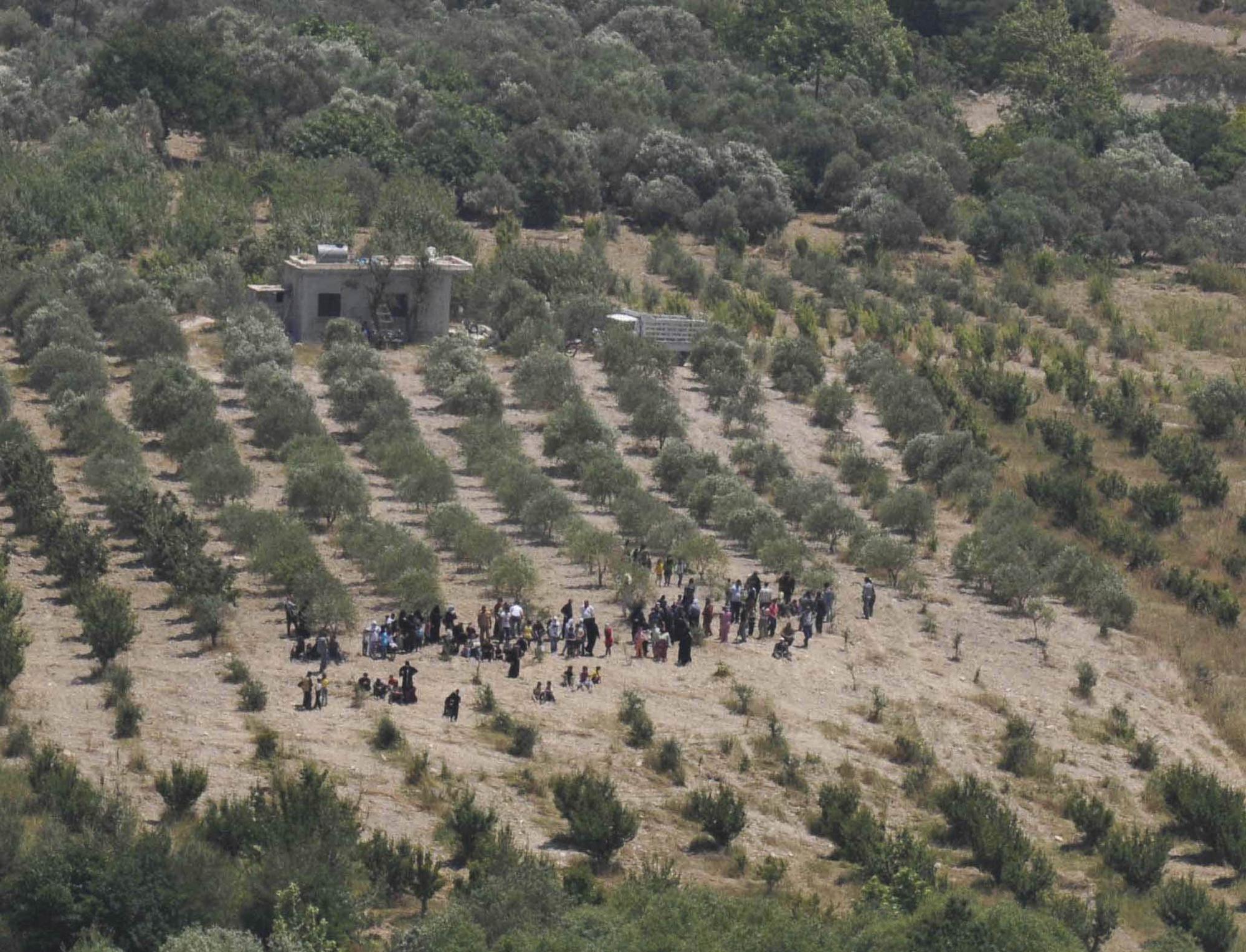Mercredi, des Syriens attendaient sur une aire agricole de pouvoir passer la frontière turque pour fuir une vaste opération de répression redoutée par la population. [REUTERS - Ismihan Ozguven]