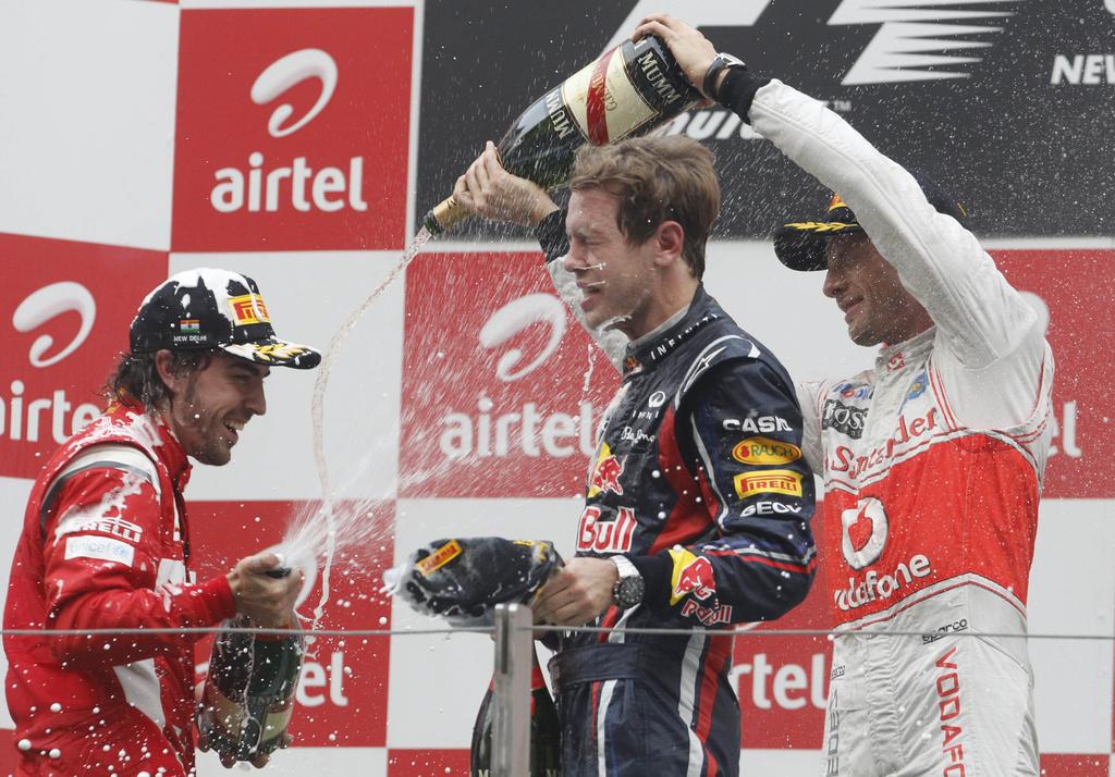 Alonso (à g.), 3e, et Button, 2e, se "vengent" au champagne sur Vettel. [KEYSTONE - Luca Bruno]