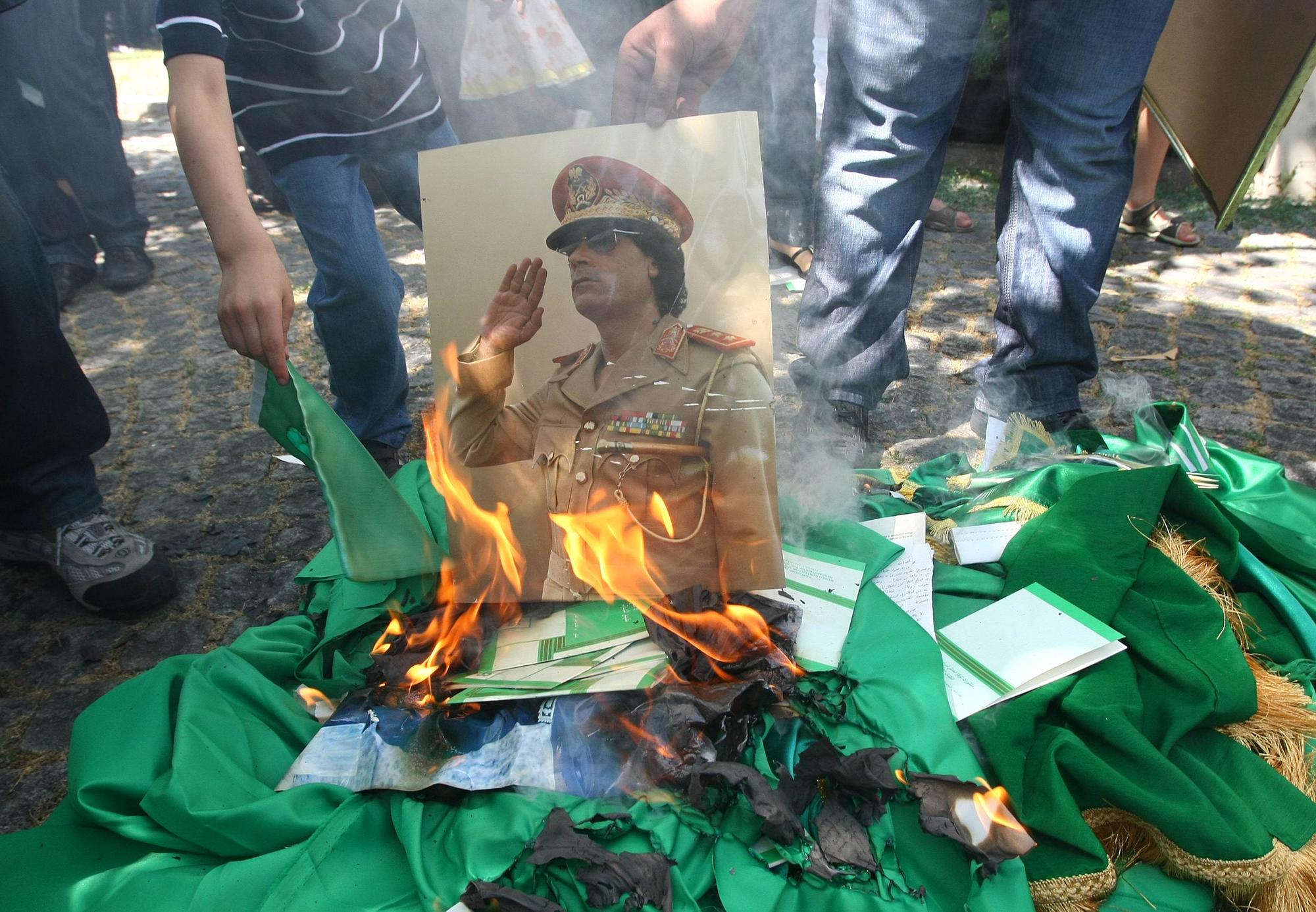 Des manifestants heureux boutent le feu à un portrait de Mouammar Kadhafi. [Adem Altan]