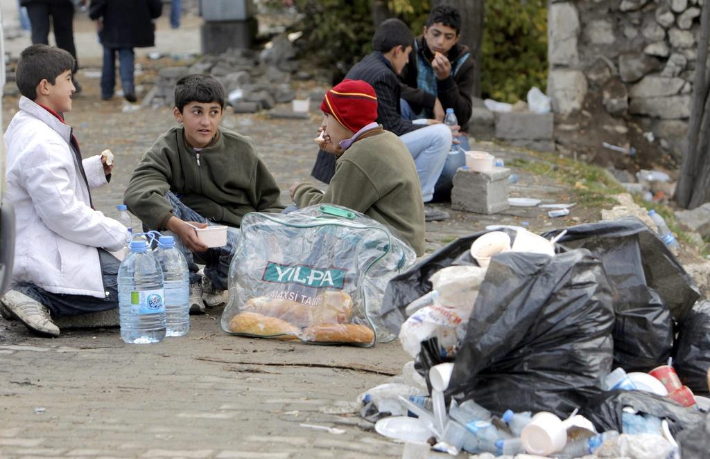 Privés de toit, ces enfants prennent leur petit-déjeuner dans la rue à Ercis. [KEYSTONE - TOLGA BOZOGLU]