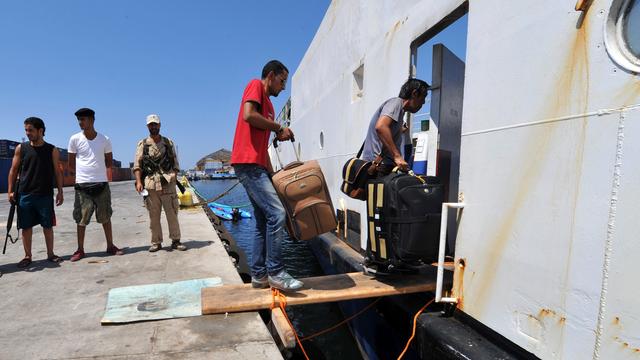 Des étrangers embarquent sur le bateau affrété par l'Organisation internationale pour les migrations (OIM).