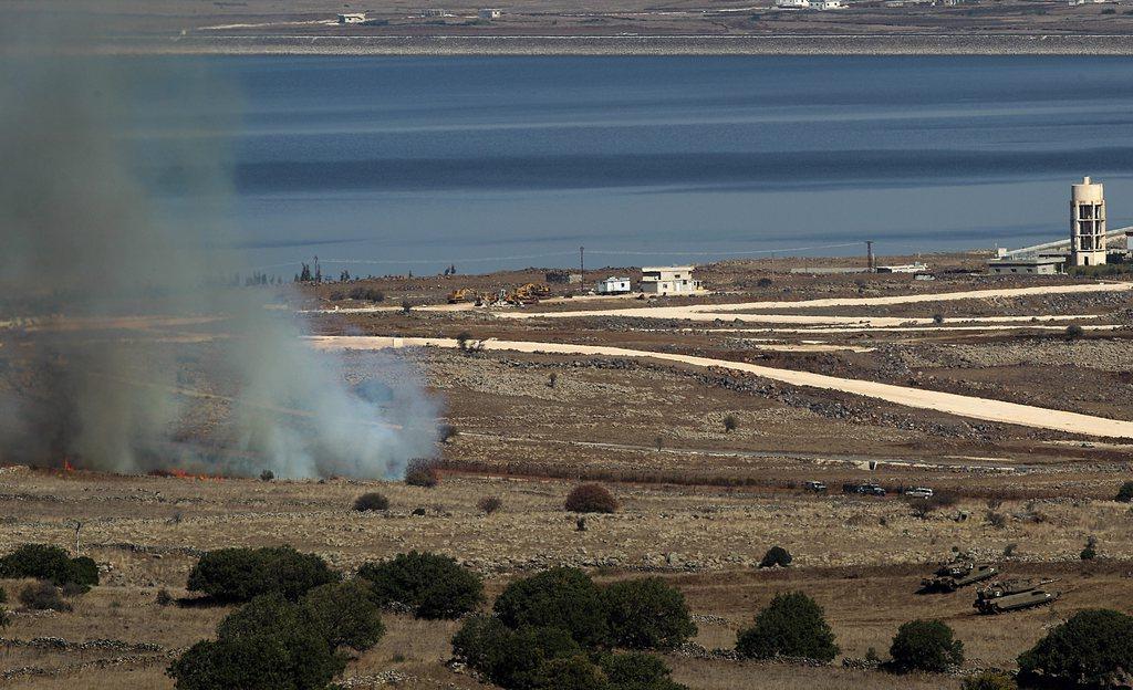 La fumée causée par la chute de l'obus de mortier venu de Syrie près de deux chars israéliens. [EPA/ATEF SAFADI]