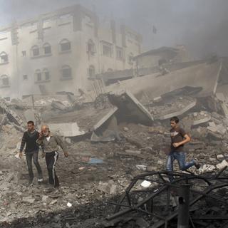Des Palestiniens fuient un bâtiment détruit par un bombardement des forces aériennes israéliennes. [Adel Hana]