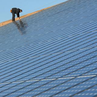 Une personne travaille sur des panneaux d'un parc photovoltaïque à Weinbourg, en  France, présenté comme la plus grande installation intégrée au monde avec ses 36'000 m². [FREDERICK FLORIN]