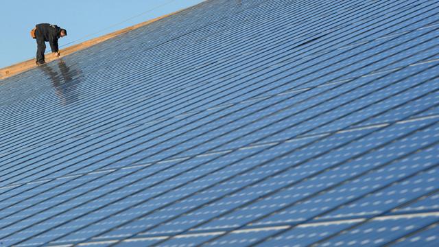 Une personne travaille sur des panneaux d'un parc photovoltaïque à Weinbourg, en  France, présenté comme la plus grande installation intégrée au monde avec ses 36'000 m². [FREDERICK FLORIN]