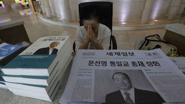 Une femme à Séoul, capitale de la Corée du Sud, prie devant des journaux annonçant la mort du fondateur de l'Eglise de l'Unification Sun Myung Moon. [Lee Jin-man]