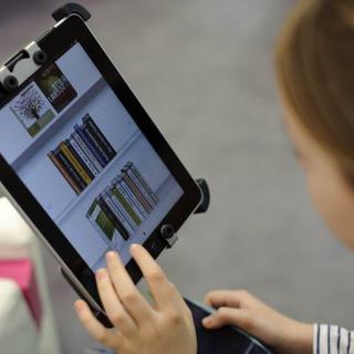 Une femme choisit un livre dans une bibliothèque sur une tablette numérique