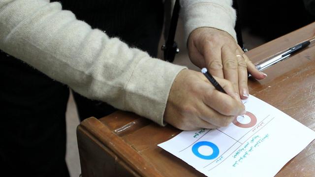 Votation sur le référendum en Egypte, une femme remplissant le bulletin de vote. [EPA - André Pain]