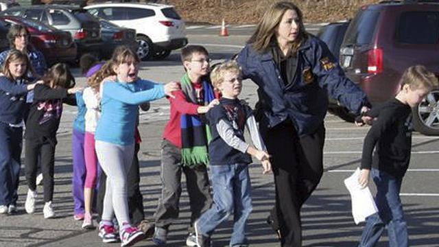 Des enfants sont évacués de l'école primaire de Newtown où s'est déroulée la fusillade. [AP Photo/Newtown Bee, Shannon Hicks]