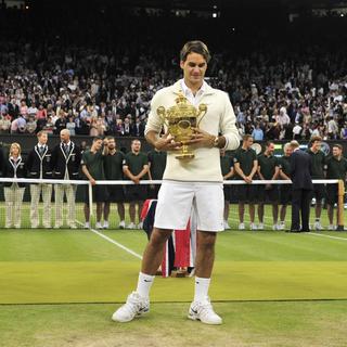 Roger Federer of Switzerland holds the winners trophy after defeating Andy Murray of Britain (L) in their men's singles final tennis match at the Wimbledon Tennis Championships in London July 8, 2012. REUTERS/Toby Melville (BRITAIN - Tags: SPORT TENNIS [Toby Melville]