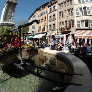 Vue de la place du Bourg-de-Four avec sa fontaine et ses terrasses dans la vieille ville de Genève. [Martial Trezzini]