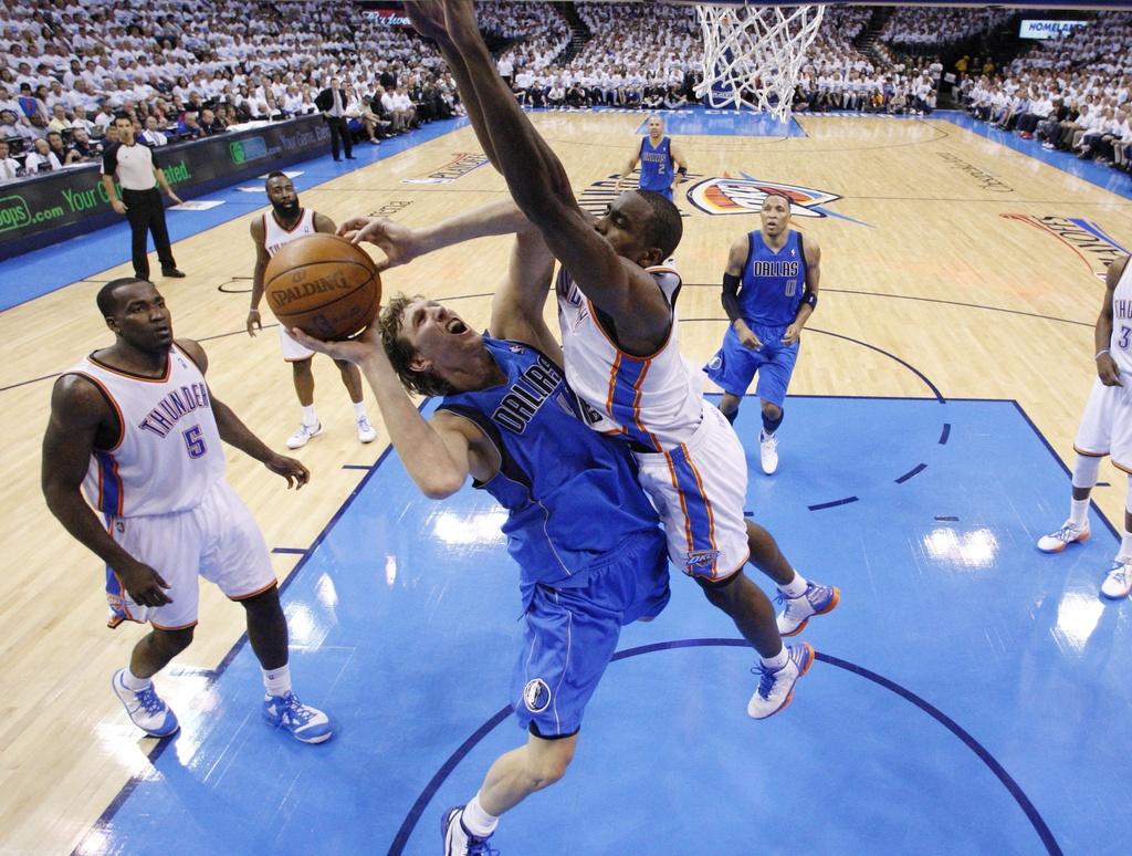 Serge Ibaka, ici opposé à Dirk Nowitzki (31 points) a défendu bec et ongles le panier d'Oklahoma. [KEYSTONE - Sue Ogrocki]