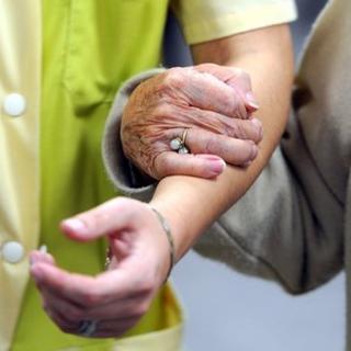 Une personne âgée marche avec une aide soignante.