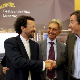 Passation de pouvoir entre Olivier Père (à droite) et Carlo Chatrian (à gauche) sous les yeux du président du festival Marco Solari. [Karl Mathis]