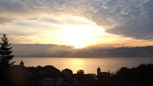 Lever de soleil jeudi au-dessus du Lac de Neuchâtel, prise depuis Grandson. On voit des cirrus et l'arrivée de quelques nuages comme des moutons. Sur le lac, on voit des vapeurs formées par l'eau plus chaude que l'air. La nuit était sans nuage et il faisait -1°C à notre thermomètre. [Caroline Rupp (9 ans)]