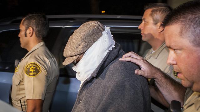 L'homme est escorté par les agents du shérif de Cerritos (Californie) à la sortie de son domicile. [REUTERS - Bret Hartman]