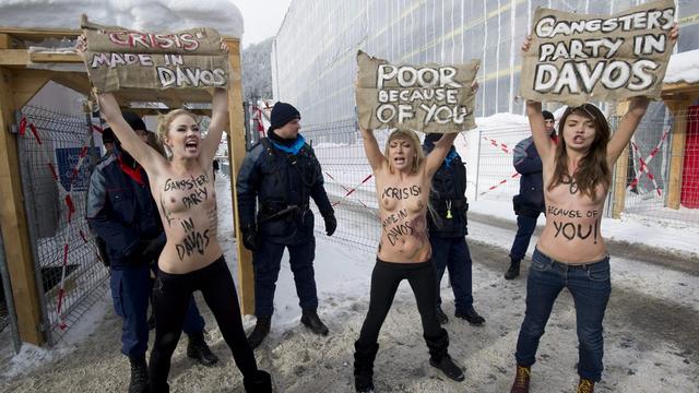 Les manifestantes se sont dévêtues devant l'entrée du WEF à Davos. [KEYSTONE - Jean-Christophe Bott]