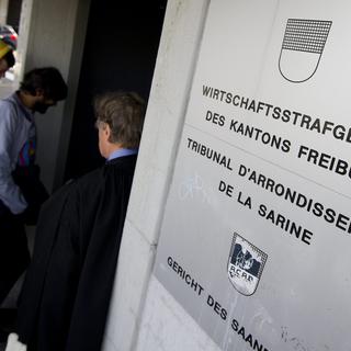 Deux manifestants et un avocat passent devant l'entrée du Tribunal de la Sarine ce mardi 8 mai 2012 à Fribourg. [Jean-Christophe Bott]