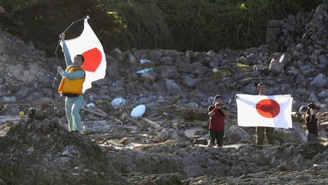 20152: des militants nationalistes brandissent le drapeau japonais sur l'une des îles Senkaku. [AP Photo/Kyodo News]