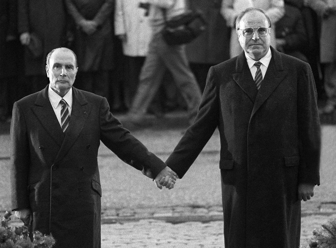 22 septembre 1984:  à Douaumont, près de Verdun, le président François Mitterrand (à gauche) et le chancelier allemand Helmut Kohl se tiennent la main en écoutant les hymnes nationaux français et allemand. Cette cérémonie de réconciliation commémore le souvenir des soldats français et allemands tombés pendant les deux guerres mondiales et scelle l'entente retrouvée. [AFP - MARCEL MOCHET]